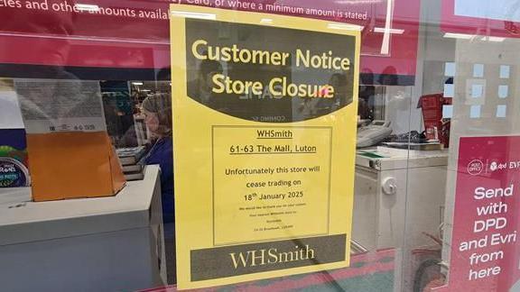 A yellow A4 piece of paper is stuck to the window of WHSmith, warning customers that the store will close on 18 January.