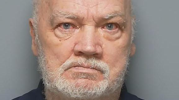 Michael Figgins glowers at the camera in a police custody photo. He has a short, white beard and his eyes are bloodshot.