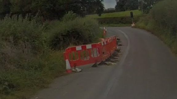 A row of red plastic barriers by the side of a rural road