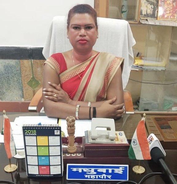 Madhu Bai, a trans woman wearing earrings and a garland of flowers around her neck