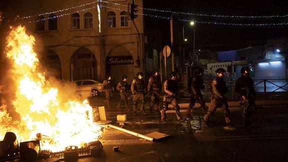 Police walking past a fire during clashes