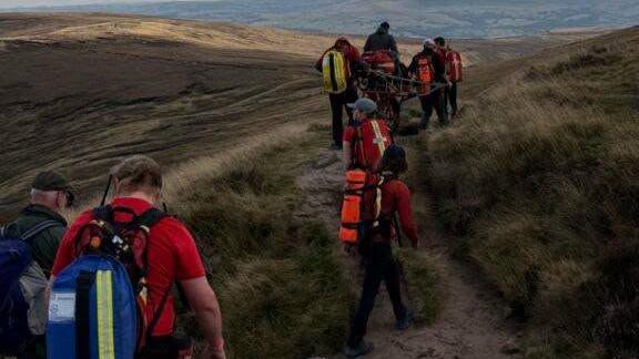 Kinder Mountain Rescue Team volunteers helping a man with a scalded foot back to safety