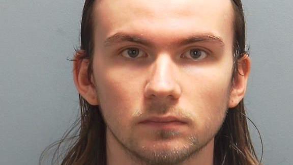 Oliver Smith has long, brown hair and stubble, in a police custody photo.