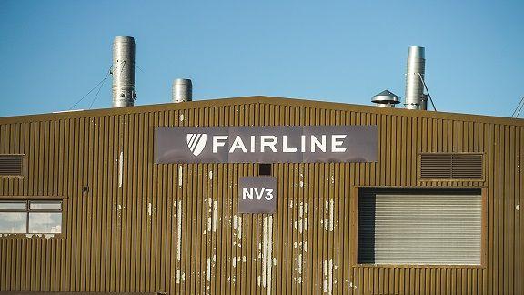 Fairline factory building made up of a brown corrugated wall with two windows and "Fairline NV3" written on signs on the wall.