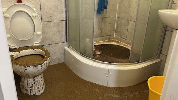 Fauzia's family bathroom in their temporary accommodation has overflowing sewage on the toilet seat, floor and inside the shower to the right of the toilet