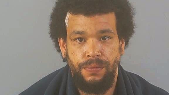 Marvin Geddes has a curly, brown hair and a full beard in a police custody photograph.