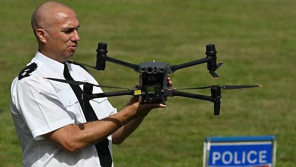 A police inspector holds up a black drone during a police demonstration.