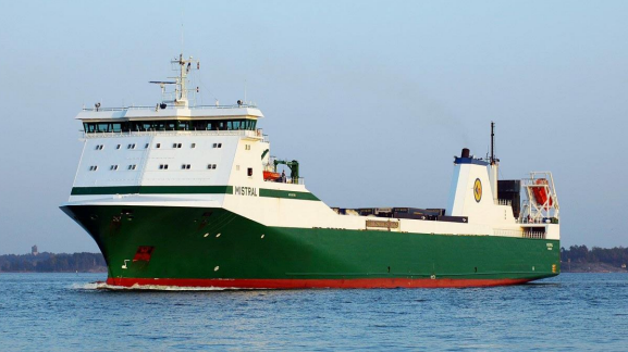 A long ship with a green hull with a white top and the name Mistral on the side. 