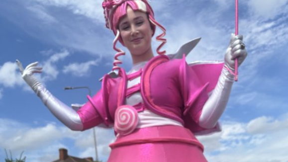 A woman dressed in pink fancy dress outfit with a pink wand and pink hair