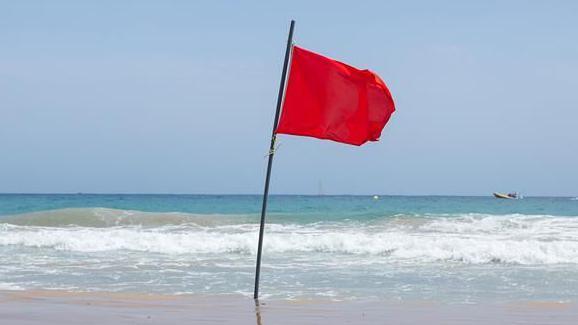 A red flag stuck in the sand