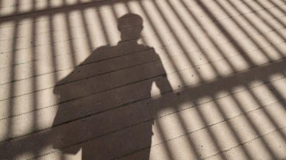 Shadow of boy looking through gate.