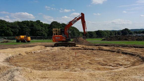 A digger creating a hole in a field for the new storm overflow