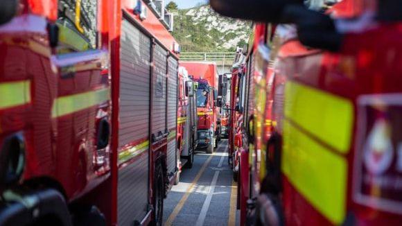 A small gap between a fleet of fire engines parked next to each other. They are painted red and yellow.
