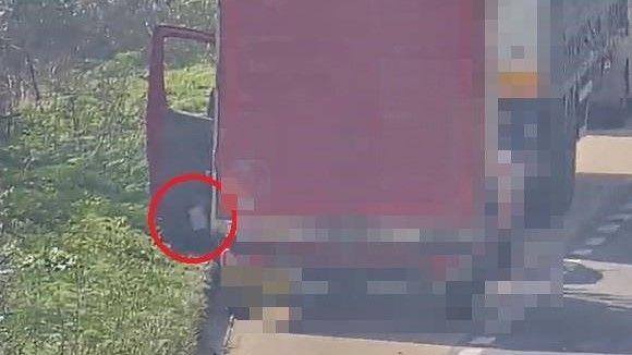 A red van parked in a layby behind a lorry. The passenger door of the van is open and litter is being thrown out of it.