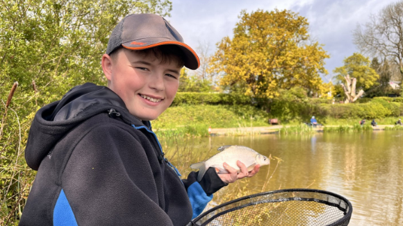 Charlie holds a fish he's caught while sitting by the lake