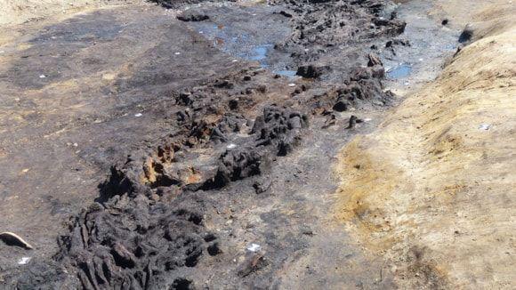 A dark, knobbly and rutted Neolithic walkway can be seen weaving on top of a bed of sandy soil  