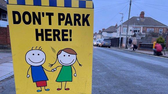 A sign warning parents about parking restrictions