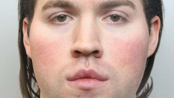 The defendant has pale skin and long brown hair.