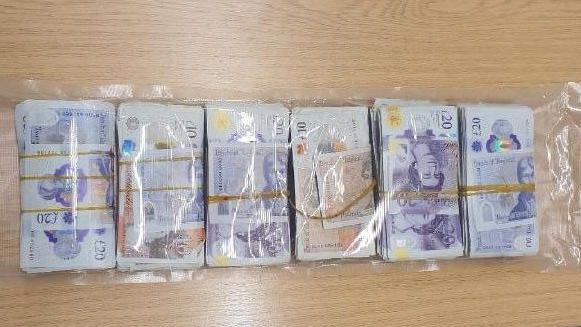 Six bundles of cash in notes all wrapped up in plastic.