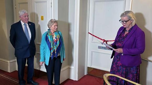 The Mary Newcombe Room was officially opened by the Chair of the Privileges and Procedures Committee, Connétable Karen Shenton-Stone. She was pictured with other guests in front of the door inside the building.