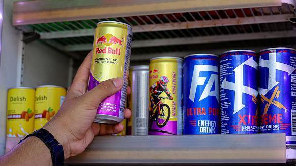 Someone taking can of energy drink off the shelf