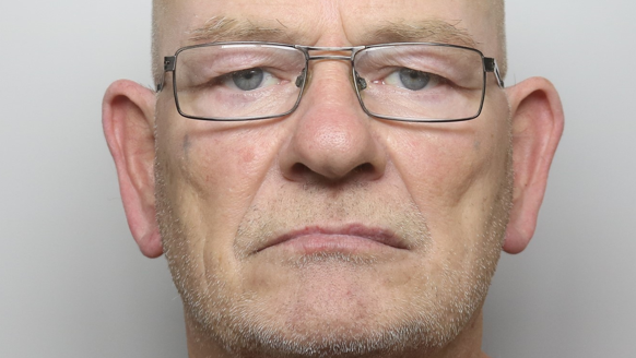 McCluskey's police mugshot shows him wearing glasses with slight stubble.