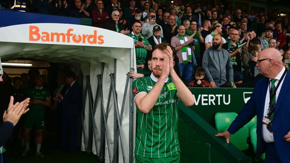 Football player in green Yeovil shirt walking out of the tunnel onto the pitch. He is applauding as he walks on.