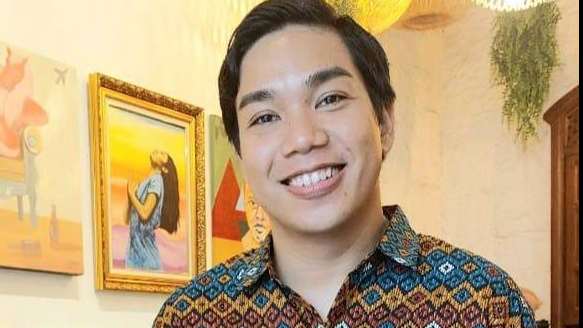 Ben Pablo, wearing a colourful shirt, smiles for a photo posted on his Facebook page. In the backdrop, paintings and a plant can be seen. 