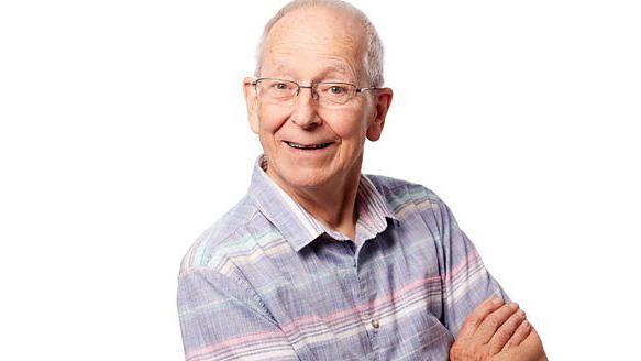 A white man wearing glasses in a striped top folds his arms and smiles for the camera