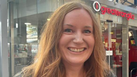 Dawn McMullan, with auburn hair, standing near the Greater Anglia customer service office at Norwich Station