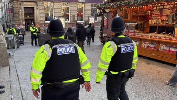 Two police officers in hi vis jackets pictured walking past stalls in Nottingham's Christmas market