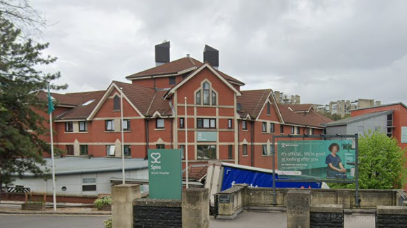 Entrance to Spire Healthcare hospital, with green sign outside saying "Spire" and an image of a heart in white.