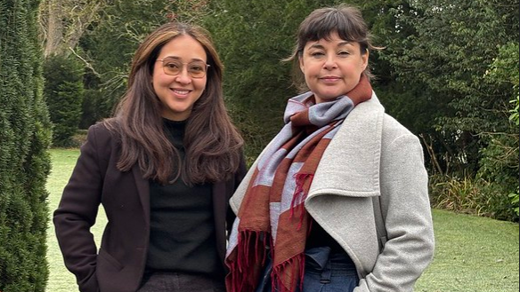 A photo showing Dr Karen Rial Lovera and Dr Cassie Newland from The Royal Agricultural University stood outside the university in Cirencester and in front of a hedge