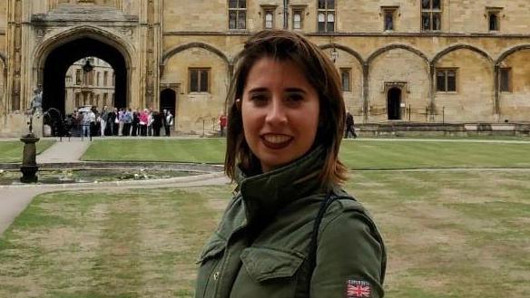 Marta Elena Vento wears a green jacket and stands on a lawn in front of a historical building