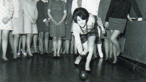 A woman bowling a ball in the social club