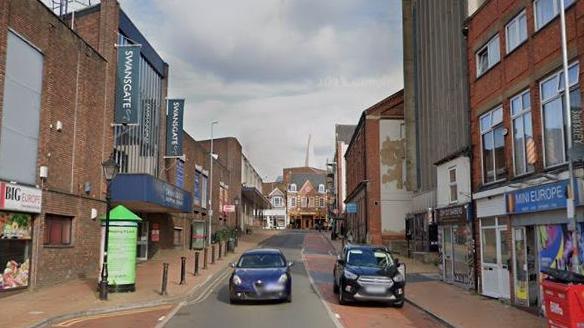 Town centre street showing shops and cars