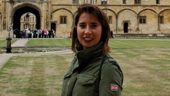 Marta Elena Vento has short, brown hair and wears a green jacket. She is pictured on a lawn outside a historical building.