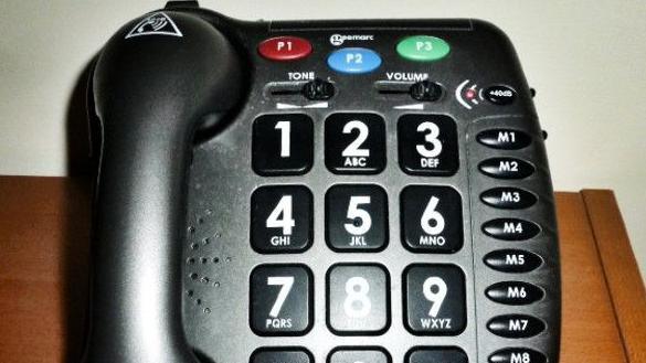 The specialist phone belonging to Mrs Sencicile. It is a traditional landline phone, made of black plastic, and has large buttons. 