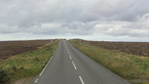 An empty road in an empty isles landscape. The sky is grey.