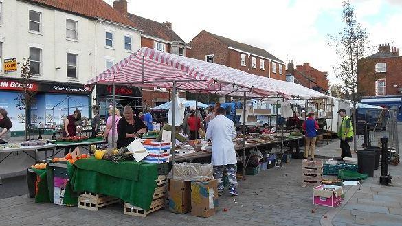 A market stall in the square with trading stalls selling fruit and veg.