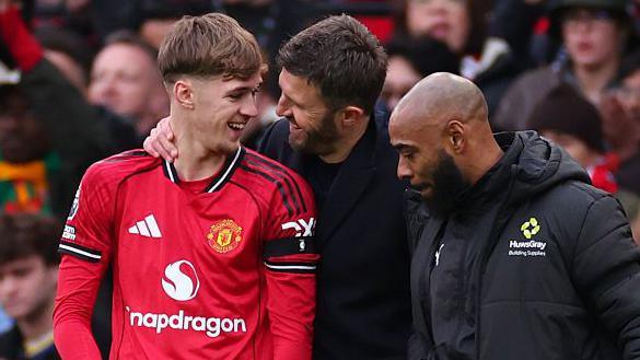 Tyler Fletcher and Michael Carrick smile at each other on the touchline