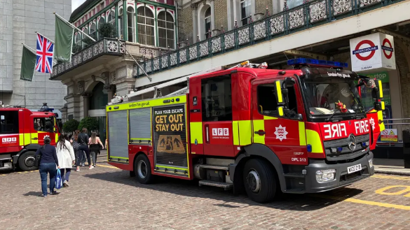 A general view of people walking beside two fire trucks which are parked outside the entrance to Charing Cross railway station in central London.