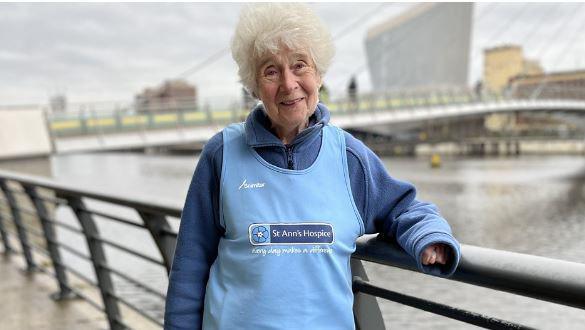 Barbara Thackray in a St Ann's Hospice bib standing by the Manchester Ship Canal