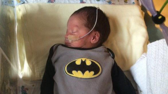 Freddie Poynter as a premature baby with a tube attached to his nose and wearing a superman baby-grow. 