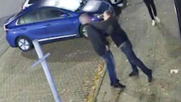 A grab from footage obtained by the Daily Mail purporting to show Mike Amesbury in a street altercation, in shot is one man appearing to punch another, on a street with a blue car in the background.