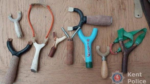 Nine handmade catapults laid on a piece of wood