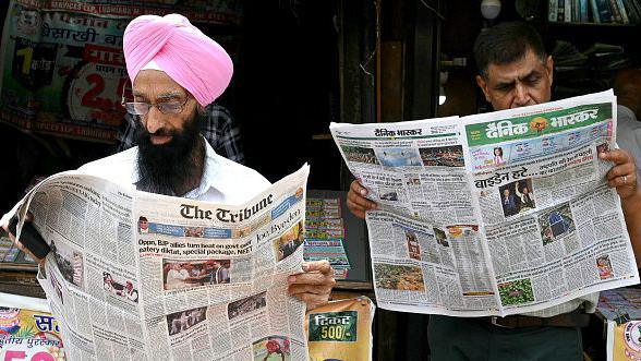 Men read local news daily with front-pages news besides a stall in Amritsar on July 22, 2024