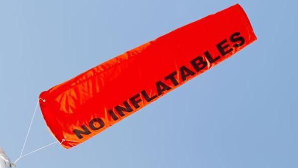 An orange cone shaped flag which has the words "NO INFLATABLES" written on it