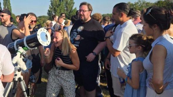 People view the eclipse via a telescope in Heaton Park in Manchester