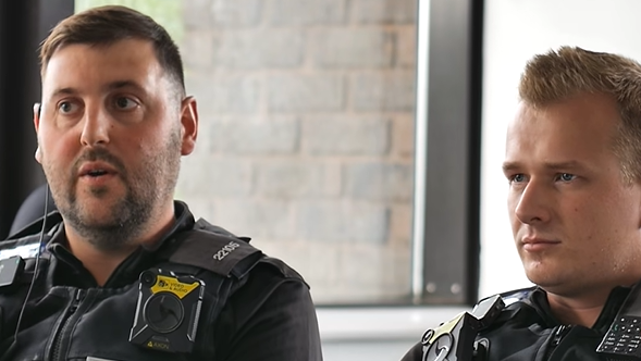 PC Oliver (left) and PC Arthur (right) in black police standard uniform. PC Oliver say short black hair with black stubble. PC Arthur is clean shaven with spikey blond hair.